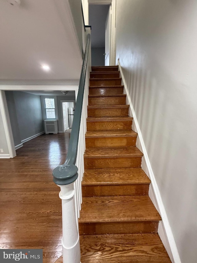 staircase featuring baseboards and wood finished floors