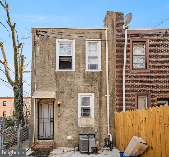 townhome / multi-family property featuring central air condition unit, a gate, fence, and stucco siding