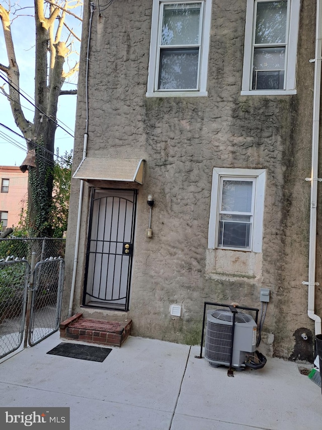 doorway to property with a gate, fence, central AC, stucco siding, and crawl space