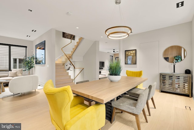 dining area featuring stairs, an inviting chandelier, and light wood-style floors