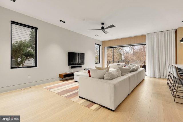 living room with light wood finished floors, a wealth of natural light, and ceiling fan