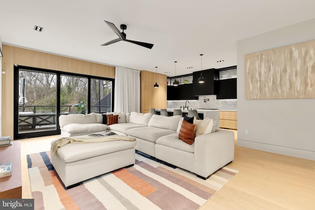 living area with light wood-type flooring and a ceiling fan