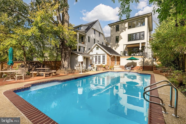 view of swimming pool with a fenced in pool, an outbuilding, fence, and a patio area