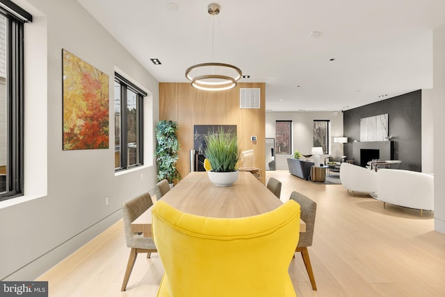 dining room featuring an accent wall, visible vents, and light wood-type flooring