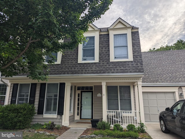 view of front of property with covered porch, an attached garage, a shingled roof, and driveway