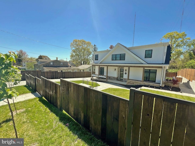 exterior space with a fenced front yard, stone siding, a patio area, and a front yard