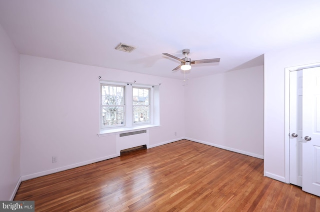 spare room featuring light wood-type flooring, visible vents, baseboards, and radiator