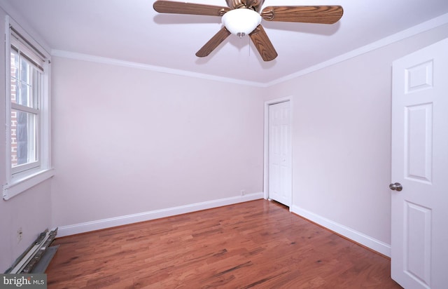 spare room featuring ceiling fan, wood finished floors, baseboards, and ornamental molding