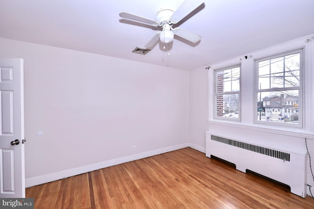 unfurnished room with visible vents, radiator, baseboards, and light wood-style floors