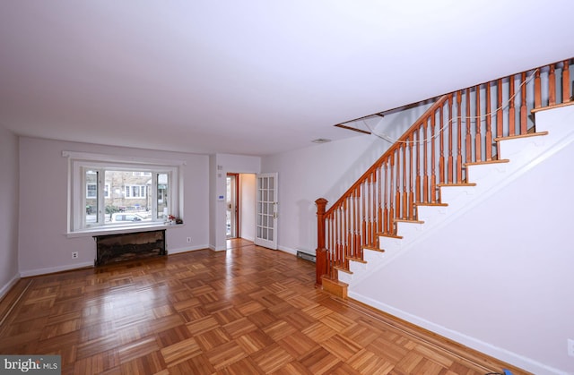 foyer with stairway, baseboards, baseboard heating, and visible vents