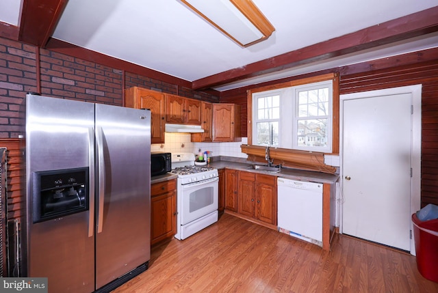 kitchen with under cabinet range hood, light wood-type flooring, beam ceiling, white appliances, and a sink