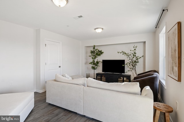 living area with plenty of natural light, visible vents, and dark wood-style flooring