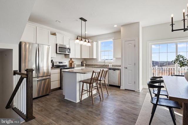 kitchen featuring stainless steel appliances, dark wood-style floors, white cabinets, and a center island