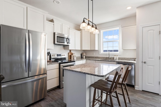 kitchen featuring a breakfast bar area, dark wood-style flooring, a sink, appliances with stainless steel finishes, and a center island