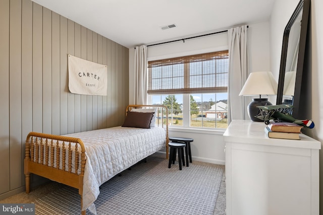 bedroom featuring visible vents, carpet flooring, baseboards, and wooden walls