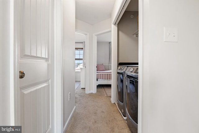 clothes washing area featuring washer and dryer, baseboards, light carpet, and laundry area