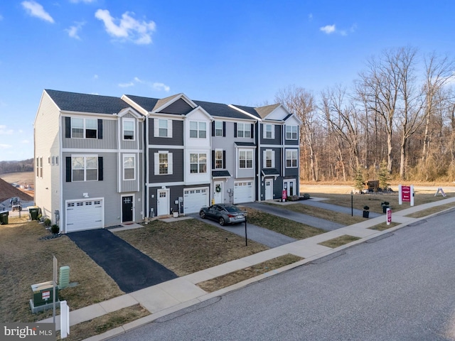 townhome / multi-family property featuring aphalt driveway and an attached garage