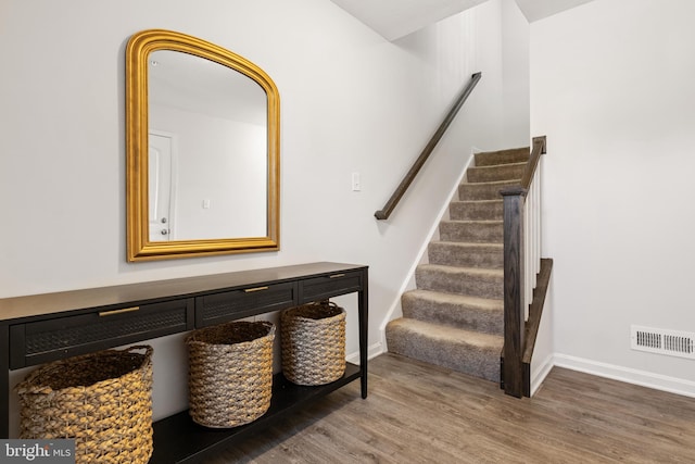 stairway with visible vents, baseboards, and wood finished floors