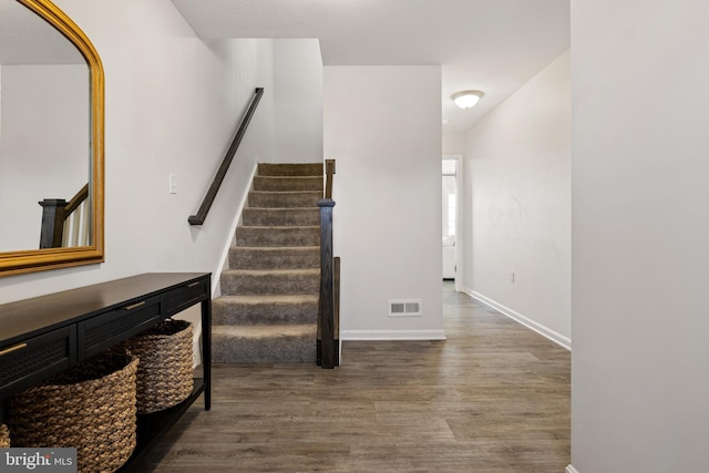 stairs featuring wood finished floors, visible vents, and baseboards