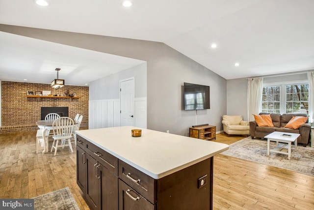 kitchen featuring light wood-style floors, dark brown cabinets, light countertops, and vaulted ceiling