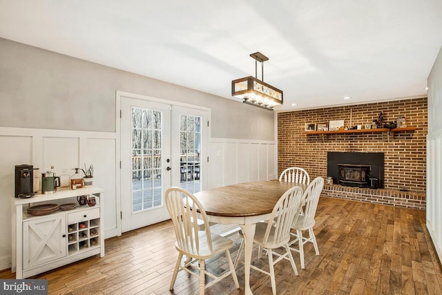 dining area featuring french doors, wood-type flooring, a wainscoted wall, and a decorative wall