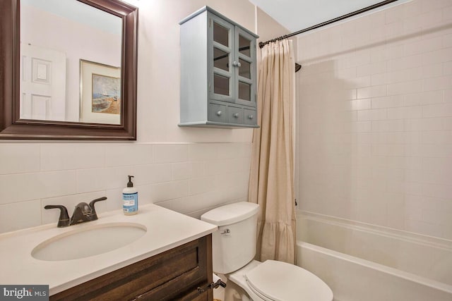 full bathroom with vanity, toilet, tile walls, and shower / tub combo