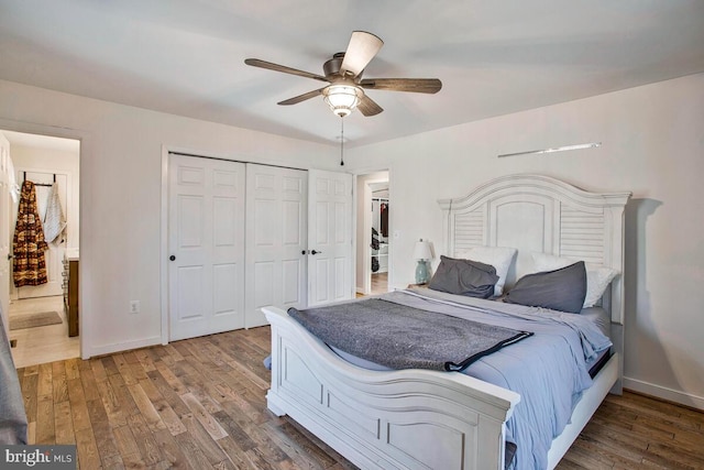 bedroom featuring baseboards, ensuite bathroom, wood finished floors, a closet, and a ceiling fan