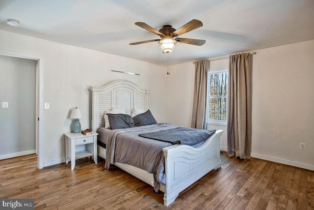 bedroom with a ceiling fan, baseboards, and wood finished floors