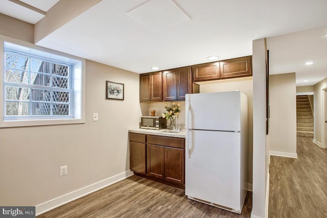 kitchen featuring stainless steel microwave, wood finished floors, freestanding refrigerator, light countertops, and baseboards