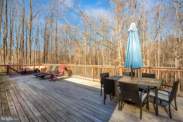 wooden deck with outdoor dining area and a view of trees