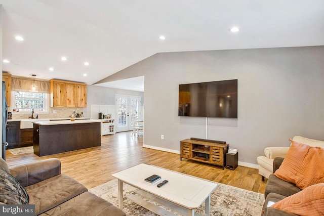 living room featuring vaulted ceiling, french doors, baseboards, and light wood finished floors