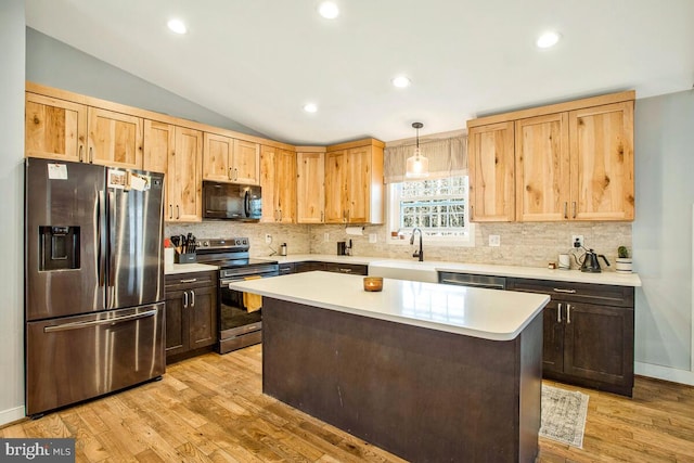 kitchen featuring lofted ceiling, a sink, light countertops, appliances with stainless steel finishes, and light wood-type flooring