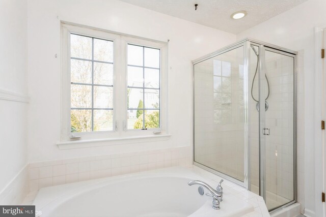bathroom featuring a bath, a healthy amount of sunlight, and a shower stall