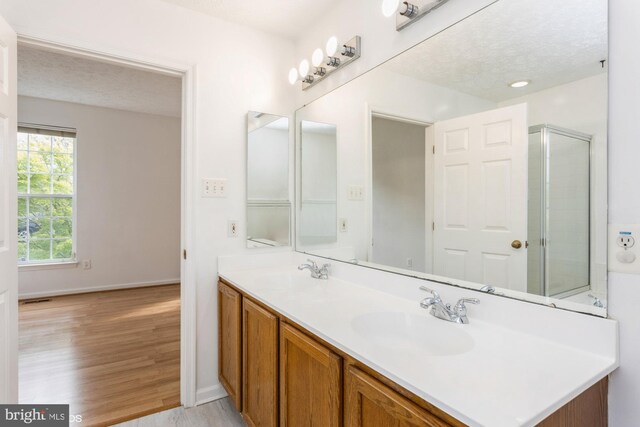 bathroom with an enclosed shower, a textured ceiling, a sink, and wood finished floors