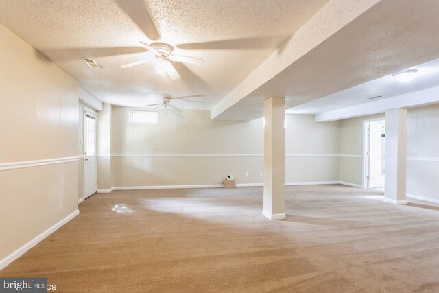 basement featuring ceiling fan, carpet floors, a textured ceiling, baseboards, and visible vents