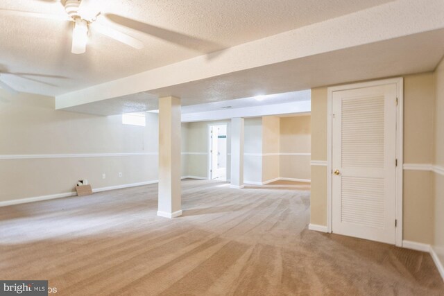 finished basement featuring baseboards, carpet flooring, a textured ceiling, and a ceiling fan