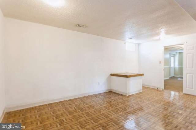 unfurnished room featuring baseboards, a textured ceiling, and visible vents