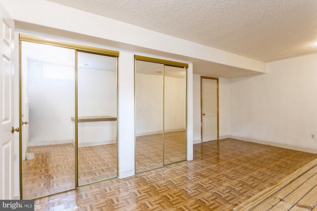 unfurnished bedroom featuring a textured ceiling and multiple closets