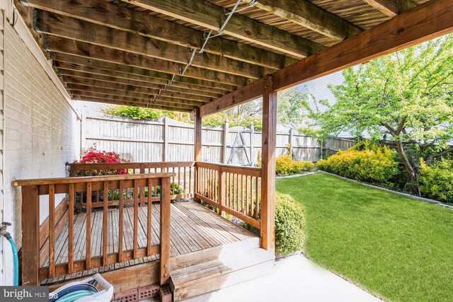 wooden terrace featuring a lawn and fence