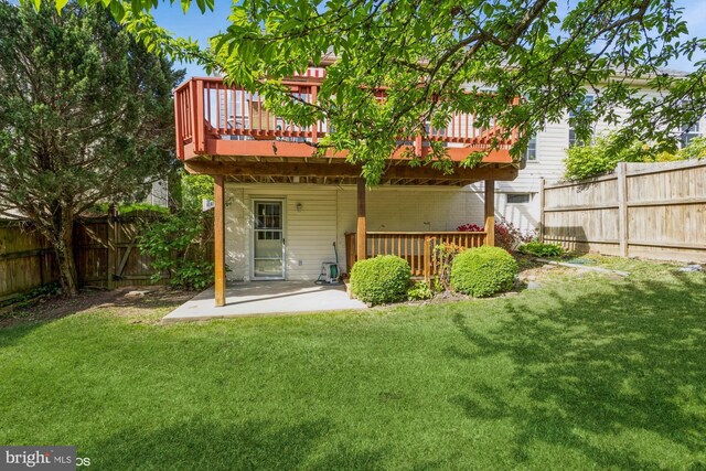 rear view of house with a fenced backyard, a wooden deck, a yard, and a patio