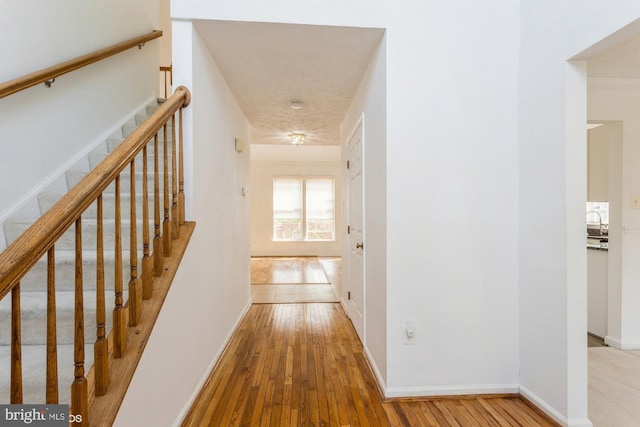 hallway featuring wood-type flooring, baseboards, and stairway