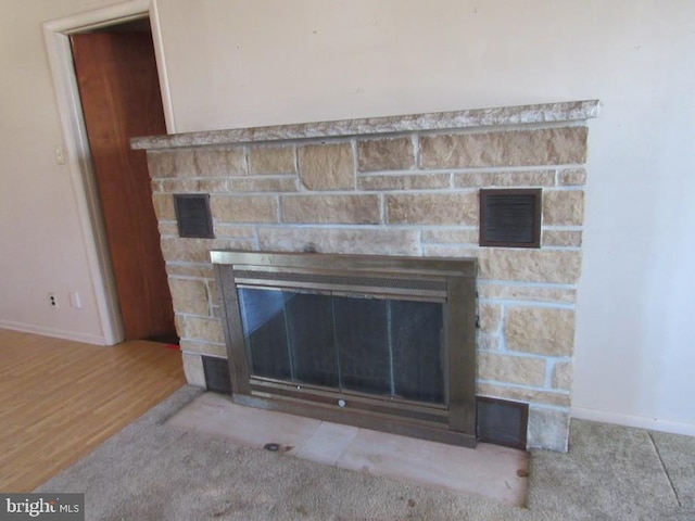 interior details featuring a stone fireplace, baseboards, carpet, and visible vents