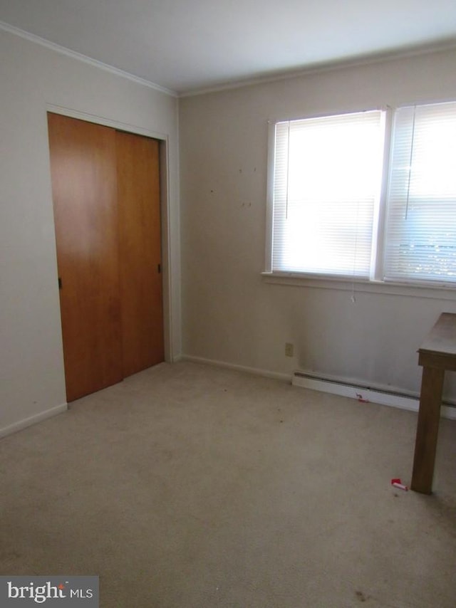 unfurnished bedroom featuring multiple windows, baseboard heating, ornamental molding, and carpet flooring