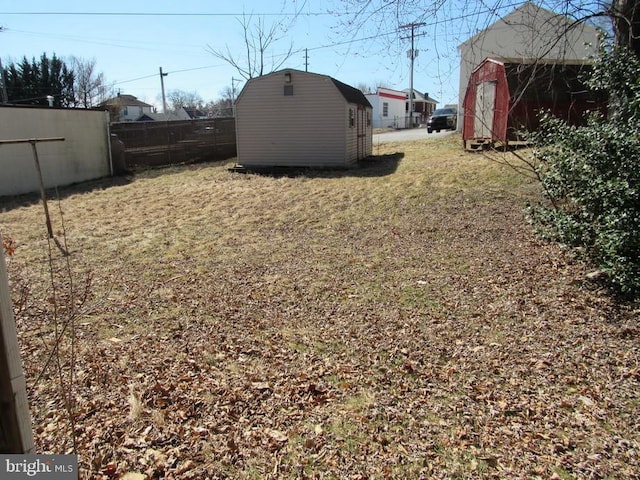 view of yard featuring a storage shed, an outdoor structure, and fence