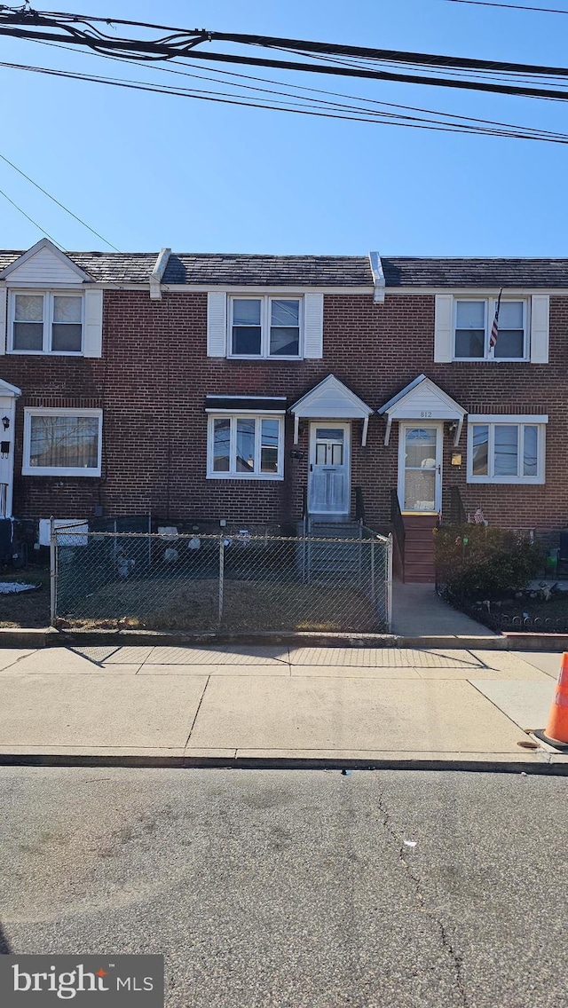 multi unit property featuring a fenced front yard and brick siding