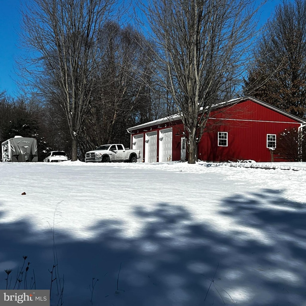 yard covered in snow featuring a garage, an outbuilding, and an outdoor structure