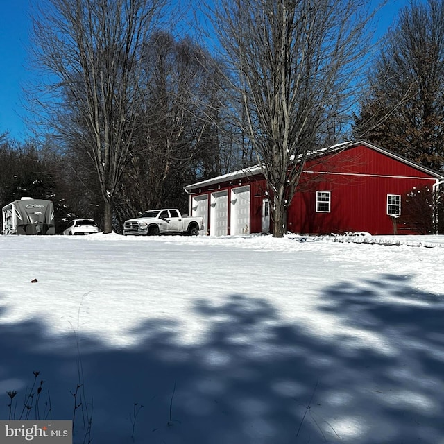 yard covered in snow featuring a garage, an outbuilding, and an outdoor structure