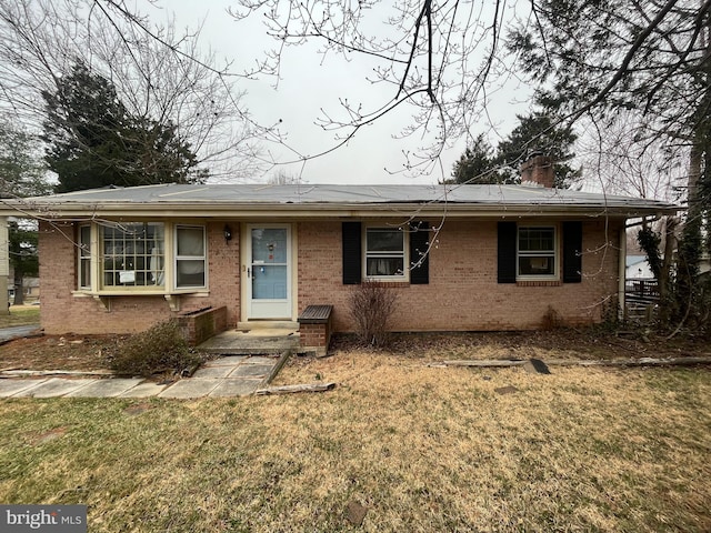 ranch-style house featuring a front lawn, brick siding, and a chimney