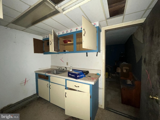 kitchen with light countertops, open shelves, and a sink