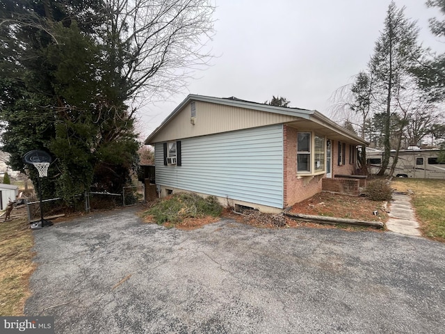 view of property exterior with aphalt driveway and fence